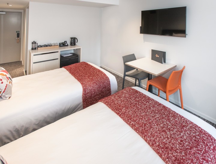 Two single beds, a TV and a kitchenette in a room at Hotel Give
